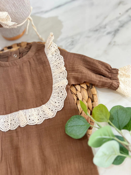 Kahverengi tulum giymiş kız ve kahverengi şapka takıyor