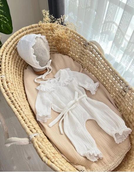 Beyaz fisto detaylı müslin tulum ve şapka seti, yenidoğan bebekler için tasarlanmıştır.