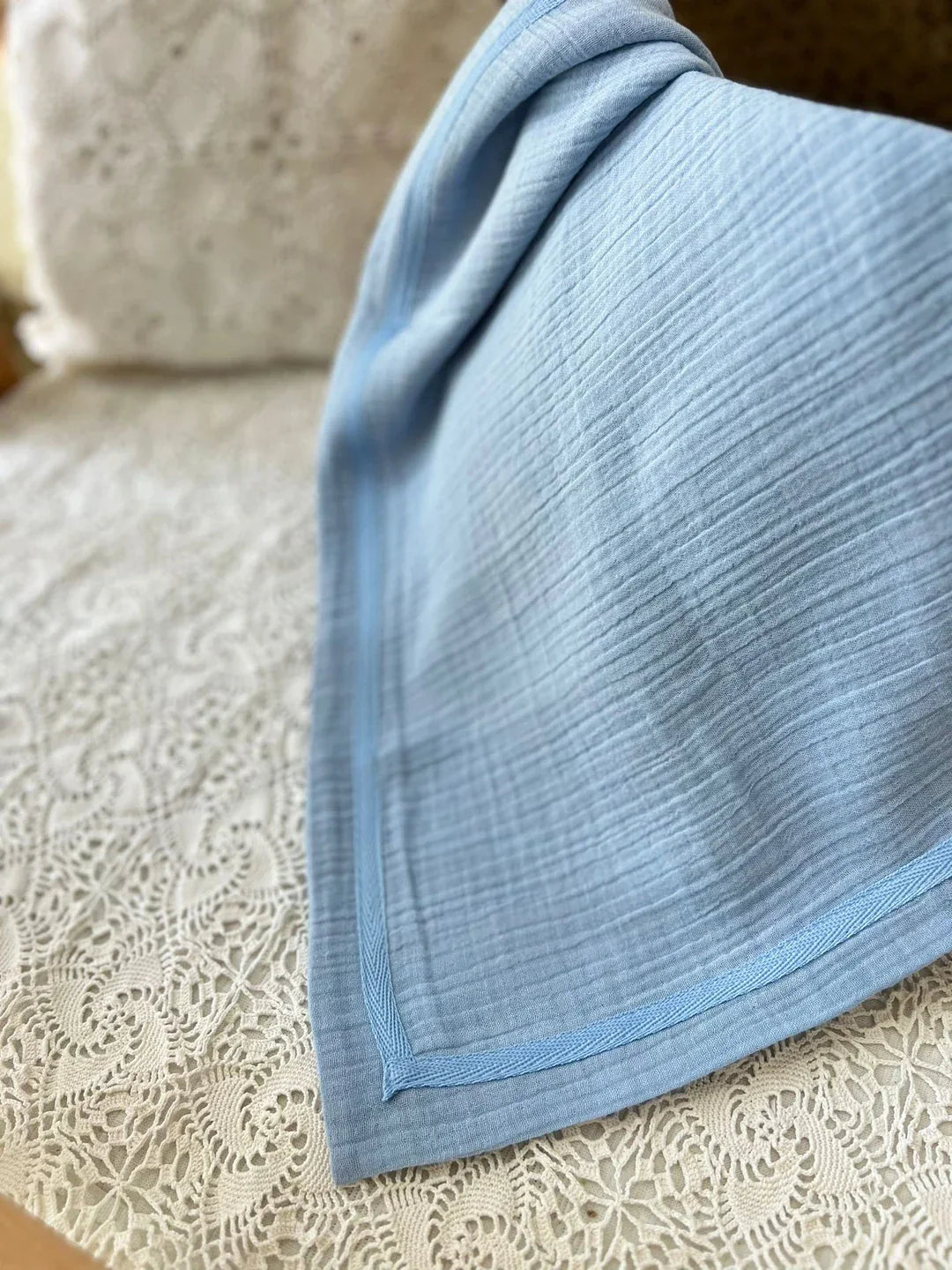 Dört katlı, %100 pamuk müslin bebek battaniyesi, bebe mavi renginde ve yumuşak dokuda.