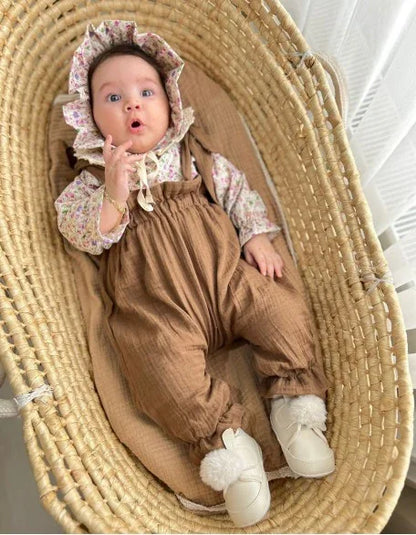 Çiçek desenli salopet, uzun kollu üst ve uyumlu şapka içeren kız bebek giyim seti.