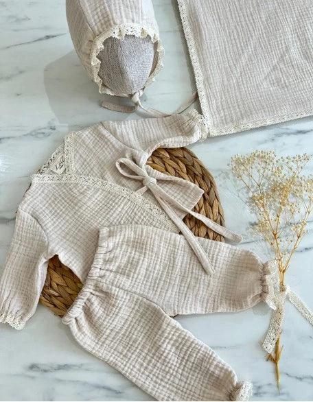 Krem renkli kız bebek seti, üst, alt ve başlık içeriyor.